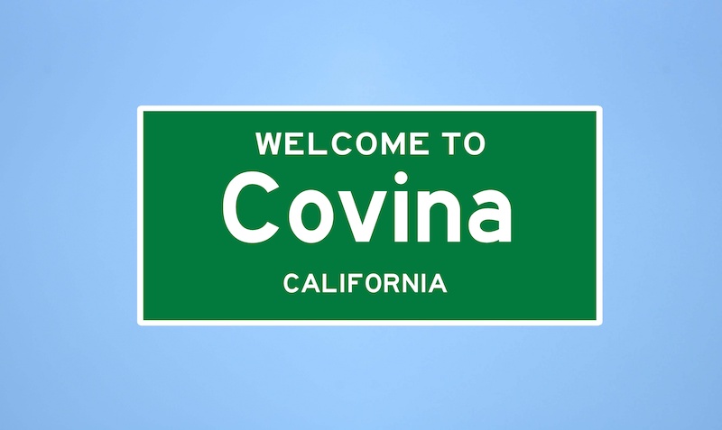 Isolated US city limit sign of Covina, located in Los Angeles county, California. Place name sign from the USA on blue background.